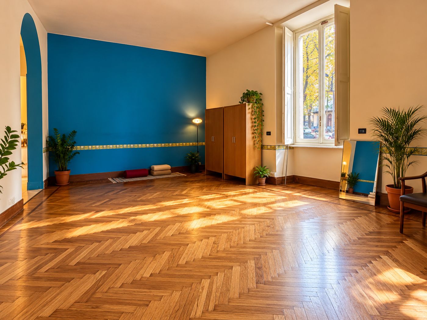 La sala d’attesa dello studio, con parquet a spina di pesce, parete blu e luce dalle finestre sul corso